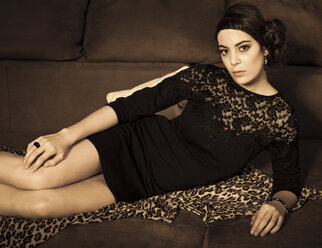 Portrait of young woman with little black dress lying on couch - FCF000004