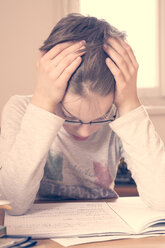 Portrait of little boy with head in his hands doing homework - LVF001035