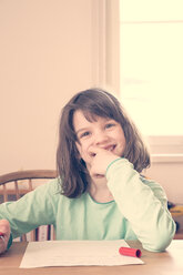 Portrait of smiling little girl doing homework - LVF001043