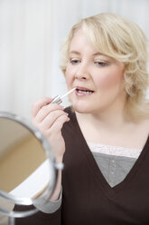 Blond woman applying make up - ECF000541