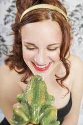 Porträt einer lächelnden jungen Frau, die einen Frosch küsst - ECF000525