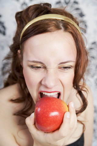 Porträt einer jungen Frau, die einen roten Apfel isst, lizenzfreies Stockfoto