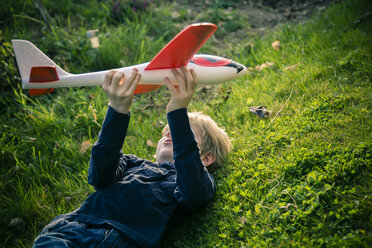 Germany, Bavaria, Landshut, Boy playing with toy aeroplane - SARF000479