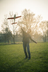 Germany, Bavaria, Landshut, Boy playing with toy aeroplane - SARF000480