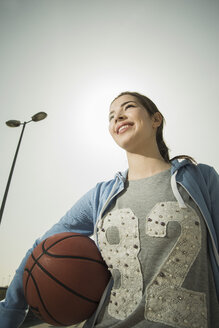 Brünette junge Frau hält Basketball im Freien - UUF000218