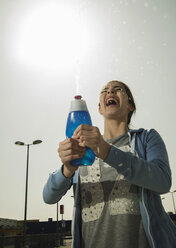 Junge Frau spritzt Wasser aus einer Flasche - UUF000219