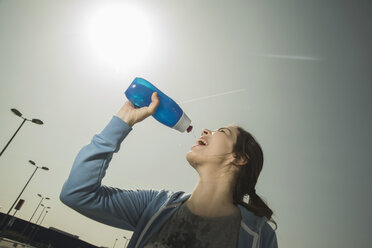 Junge Frau trinkt Wasser aus einer Flasche - UUF000310