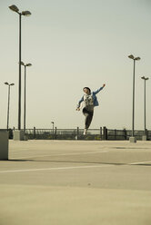 Young woman with skateboard jumping on parking level - UUF000223