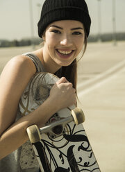 Porträt einer lächelnden jungen Frau mit Skateboard - UUF000228