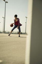 Young woman playing basketball outdoors - UUF000238