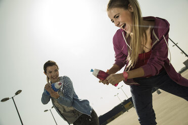 Two playful young women splashing with water bottle - UUF000250