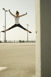 Young woman jumping mid-air on parking level - UUF000255