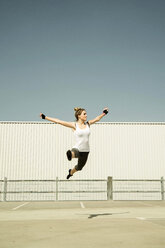 Junge Frau springt in der Luft auf einem Parkdeck - UUF000257