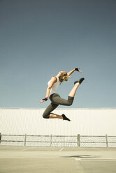 Young woman jumping mid-air on parking level - UUF000258