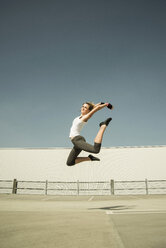 Young woman jumping mid-air on parking level - UUF000259