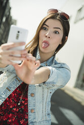 Grimacing young woman taking a selfie outdoors - UUF000273