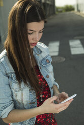 Brunette young woman using cell phone outdoors - UUF000276