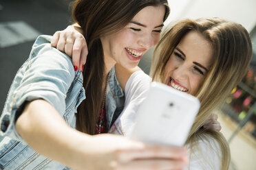 Zwei glückliche junge Frauen machen ein Selfie im Freien - UUF000280