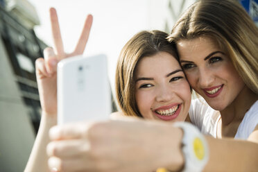 Zwei glückliche junge Frauen machen ein Selfie im Freien - UUF000281