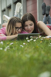 Zwei junge Frauen benutzen ein digitales Tablet auf einer Wiese - UUF000297