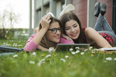 Zwei junge Frauen benutzen ein digitales Tablet auf einer Wiese - UUF000296