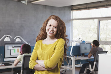 Portrait of smiling young woman in open space office - RBF001611