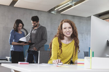 Portrait of smiling woman at her workplace in the office - RBF001624