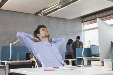 Porträt eines Mannes, der sich an seinem Arbeitsplatz im Büro entspannt - RBF001629