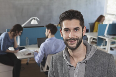 Portrait of smiling man in an open space office - RBF001637