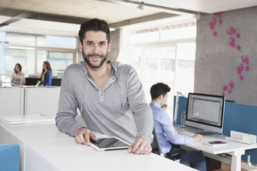 Porträt eines lächelnden Mannes mit Tablet-Computer im Büro - RBF001655