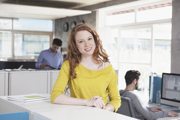 Portrait of smiling woman standing in an open space office - RBF001658