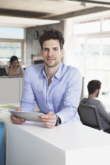 Porträt eines lächelnden Mannes mit Tablet-Computer im Büro - RBF001685