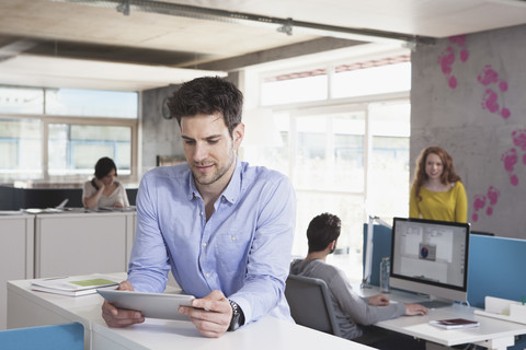 Porträt eines lächelnden Mannes mit Tablet-Computer im Büro, lizenzfreies Stockfoto