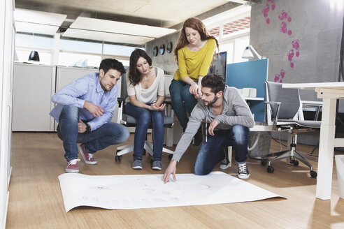 Vier Kollegen diskutieren im Büro über ein Konzept - RBF001686