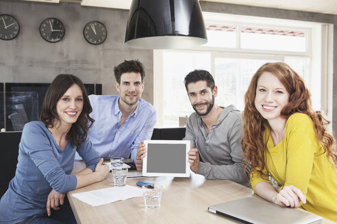 Gruppenbild von vier kreativen Menschen, die einen Tablet-Computer im Büro zeigen - RBF001672