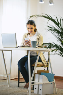 Woman with smartphone at modern home office - EBSF000186