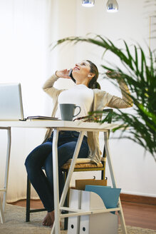 Portrait of woman telephoning with smartphone at modern home office - EBSF000185