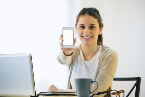 Portrait of woman showing smartphone stock photo