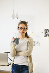 Porträt einer Frau mit Kaffeetasse in einem modernen Heimbüro - EBSF000183