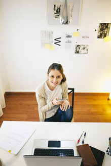 Portrait of woman with smartphone at modern home office, elevated view - EBSF000155