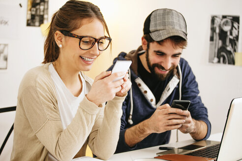 Young couple with smartphones at modern home office - EBSF000159