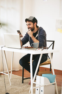 Man with smartphone at modern home office - EBSF000173