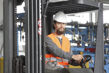 Worker with hard hat in a factory hall driving forklift - SGF000578