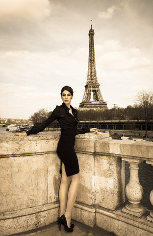 Frankreich, Paris, elegant gekleidete Frau posiert auf einer Brücke vor dem Eiffelturm, lizenzfreies Stockfoto
