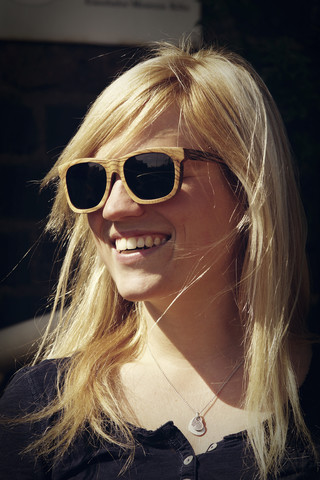 Porträt einer lächelnden jungen Frau mit Sonnenbrille, lizenzfreies Stockfoto