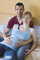 Paar, das ein Baby erwartet, sitzt zu Hause im Bett - MUF001483