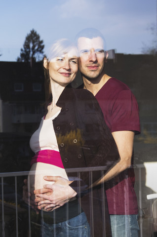 Ehepaar, das ein Baby erwartet, schaut aus dem Fenster, lizenzfreies Stockfoto