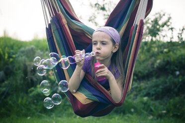 Portrait of little girl blowing soap bubbles - SARF000498