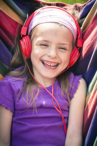 Portrait of laughing little girl with red headphones stock photo