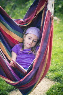 Portrait of little girl reading book in hammock - SARF000494